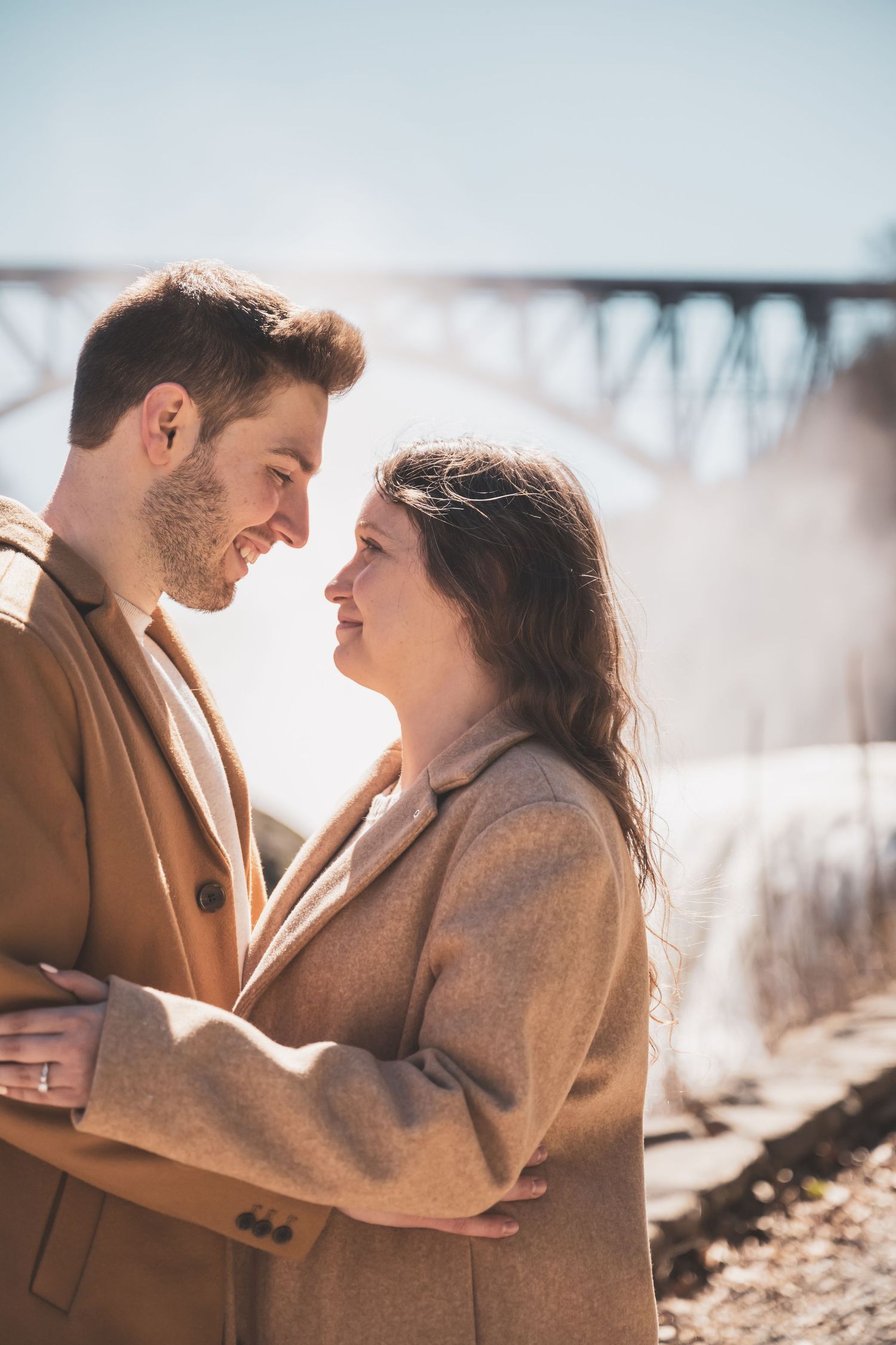 Couple in coordinated winter outfits sharing tender moments in natural sunlight.