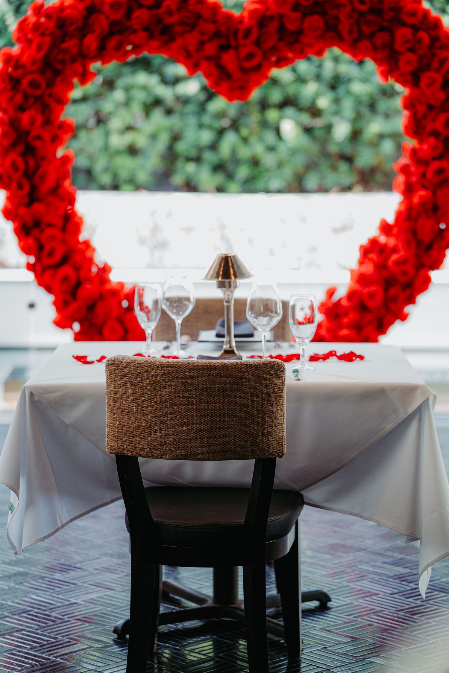 Elegant wedding reception table setting with bright red rose arch decorations and white tablecloths.