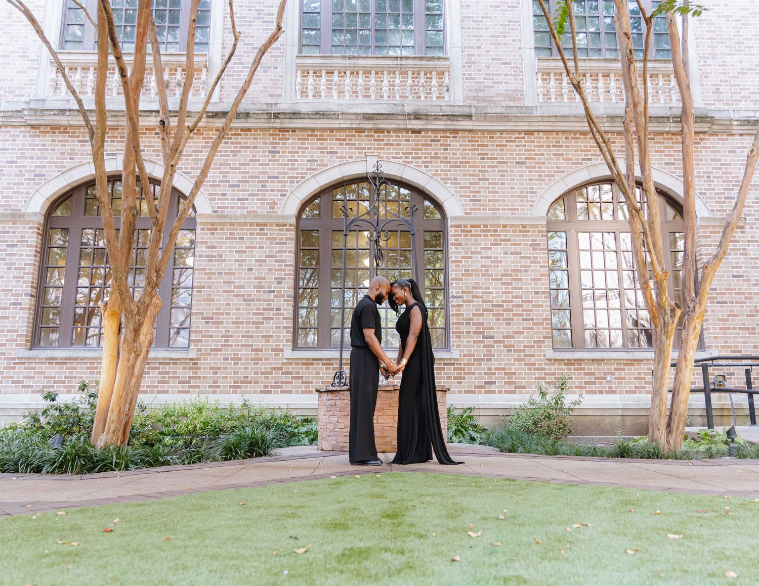 Wedding photo session in front of a brick building with trees.
