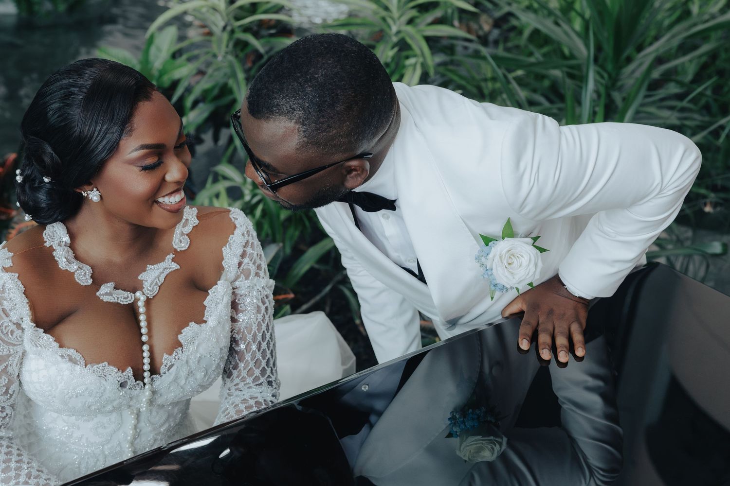 Intimate moment between newlyweds in white attire during garden reception.
