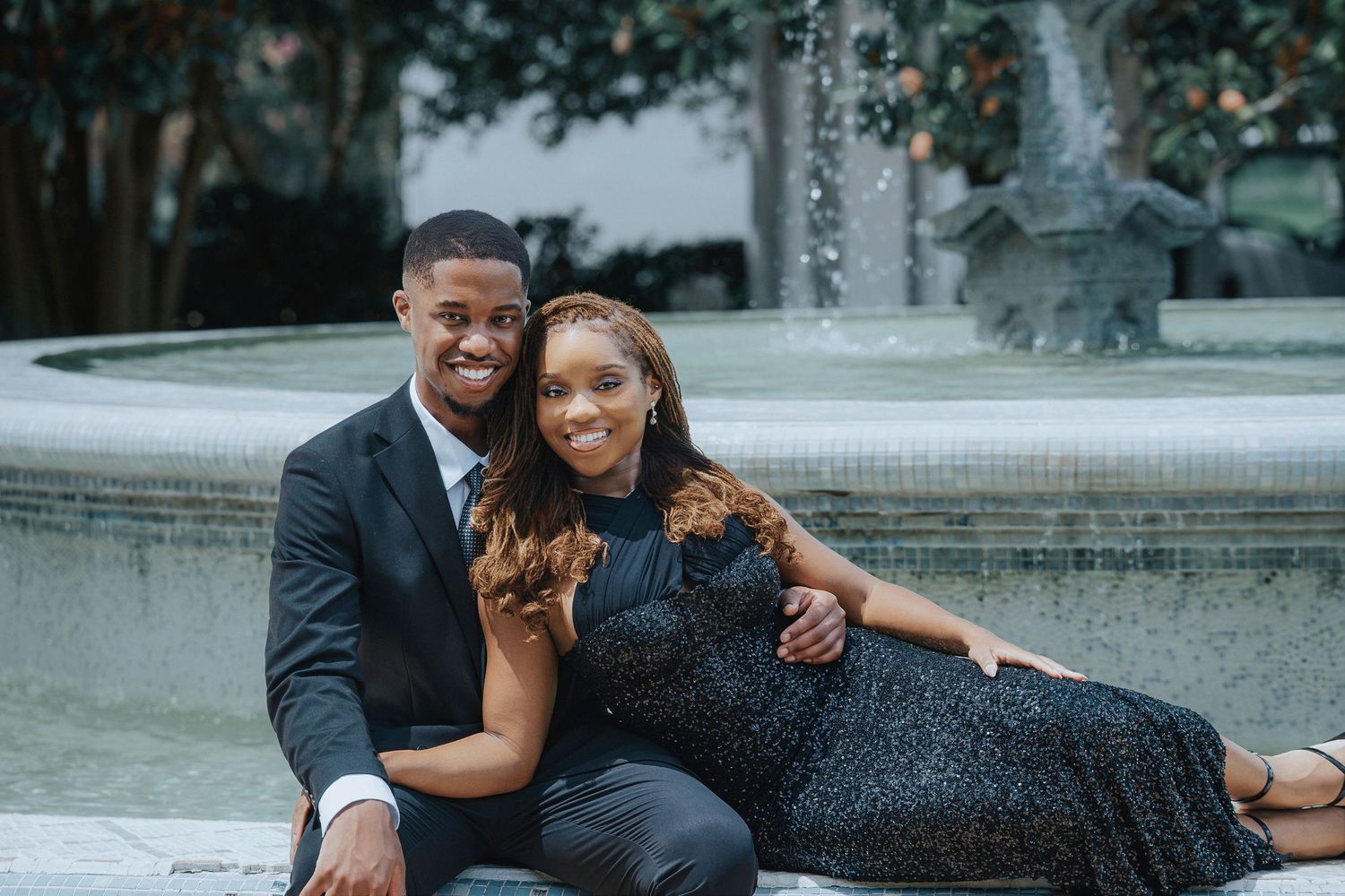 Romantic engagement photos by fountain in urban setting.
