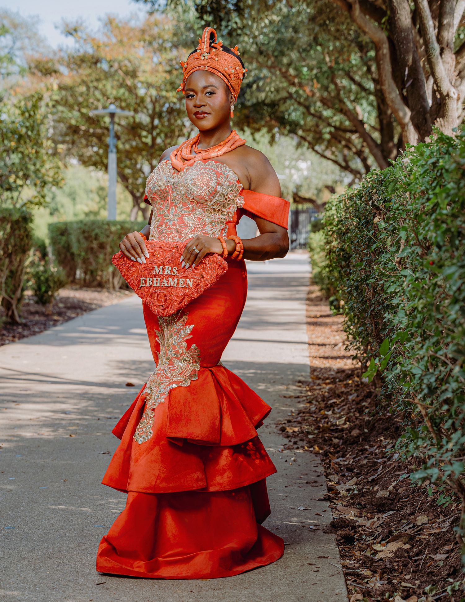 Elegant red and gold traditional mermaid gown with layered ruffles and matching coral headpiece.