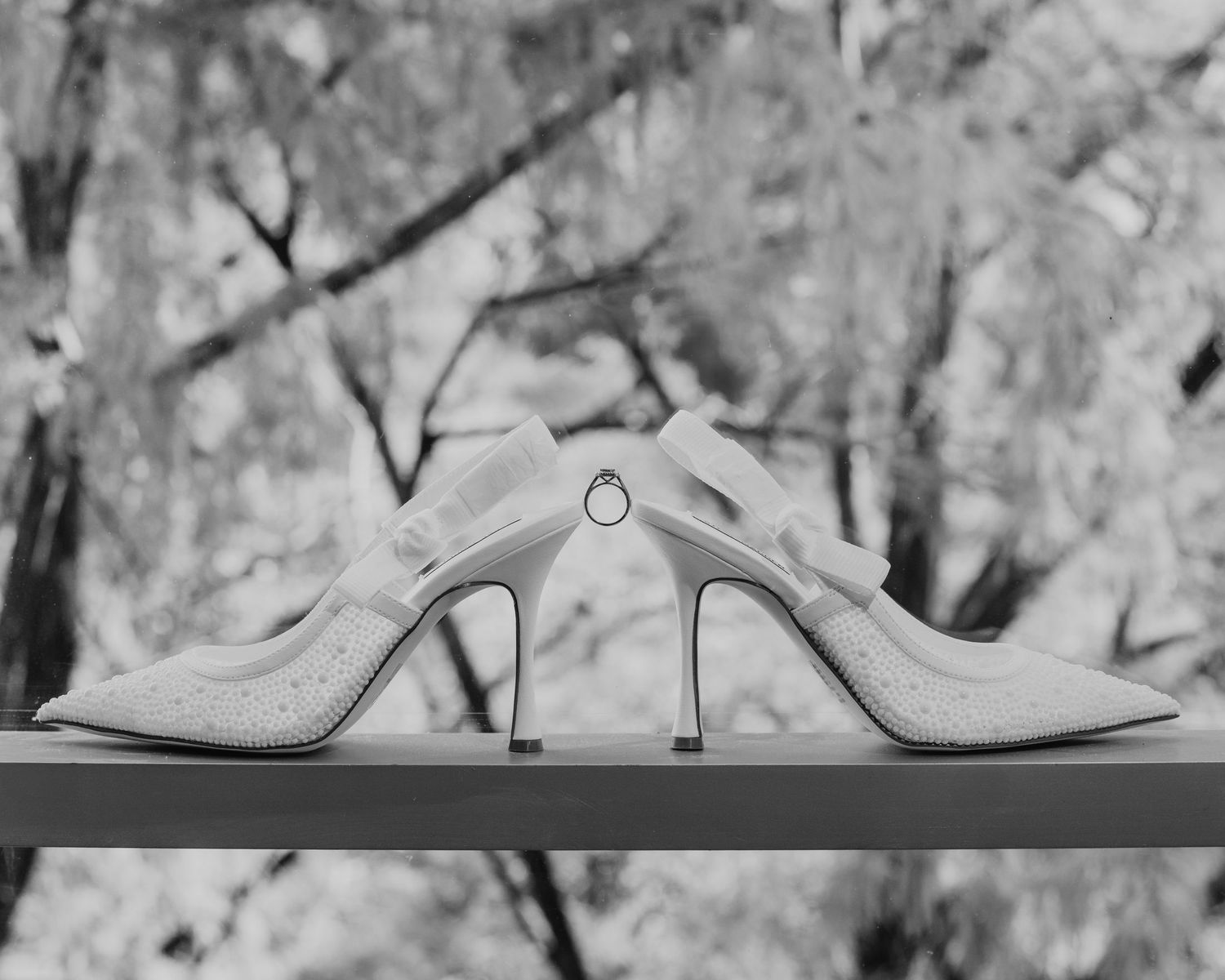 White leather mules with pointed toes and kitten heels arranged in a row against a marbled background.