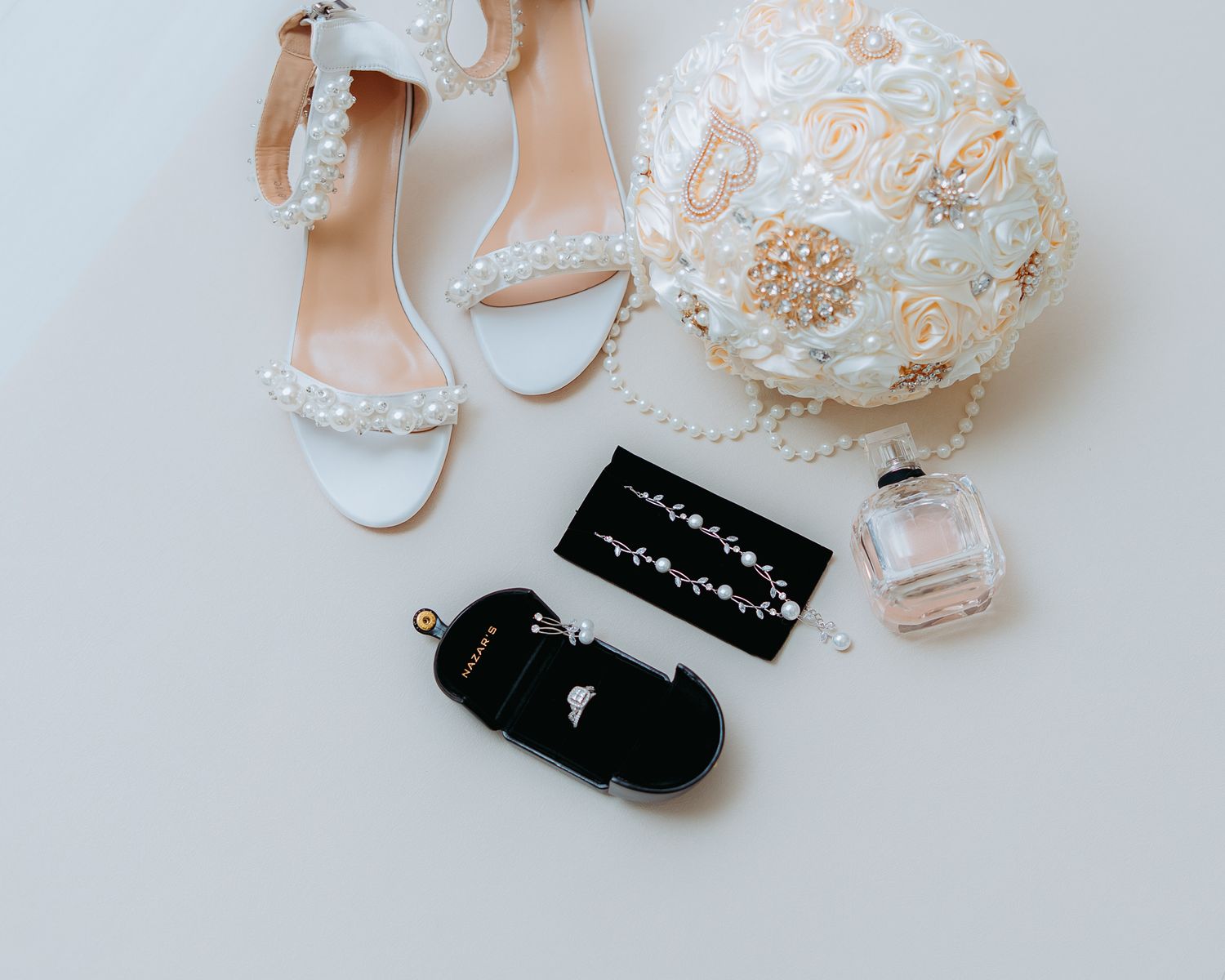 Wedding accessories including white shoes and jewelry on light background.