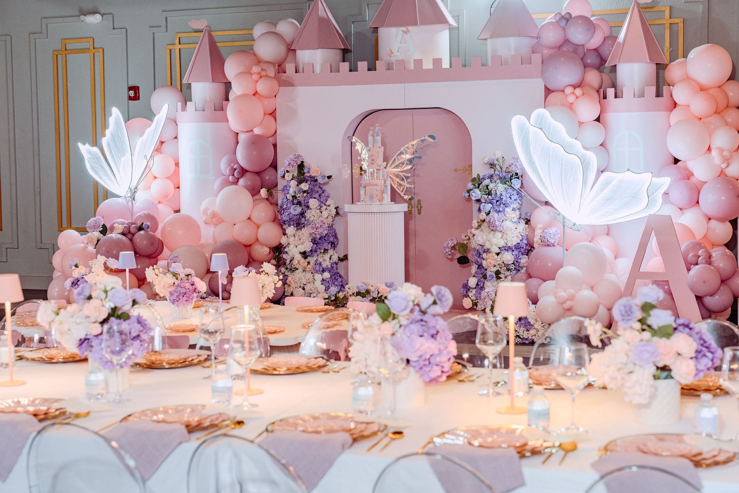 Elegant pink and white party setup with balloon arch, fairy lights, and whimsical decorations for a dreamy celebration.