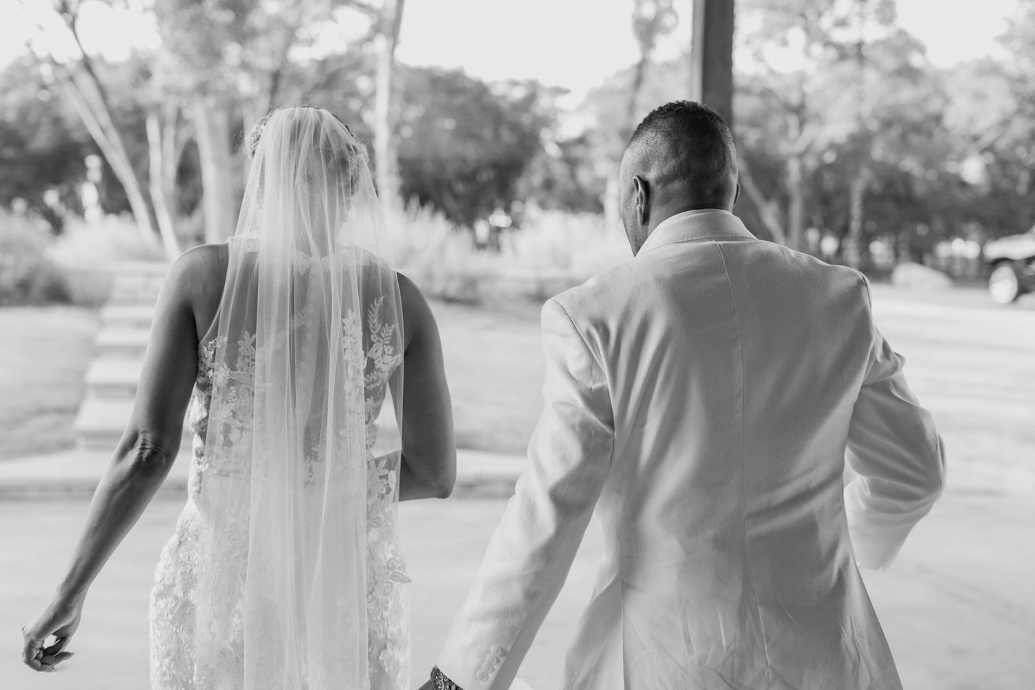 Black and white photo of newlyweds walking together outdoors.