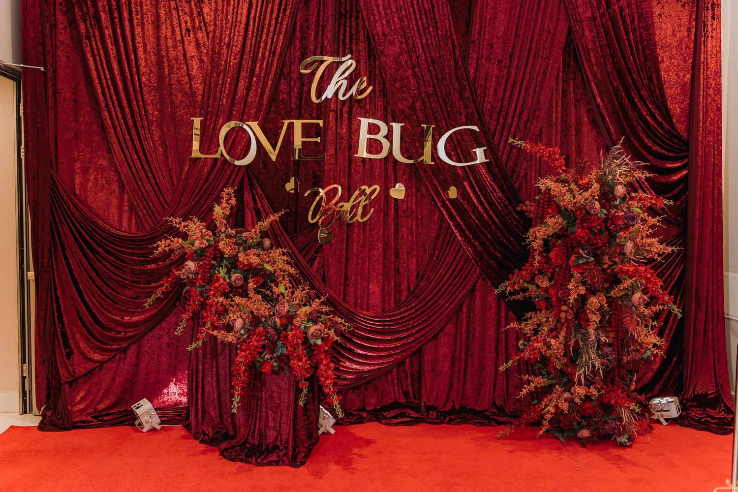 Elegant wedding venue setup with deep red velvet drapes and floral arrangements creating a romantic atmosphere.