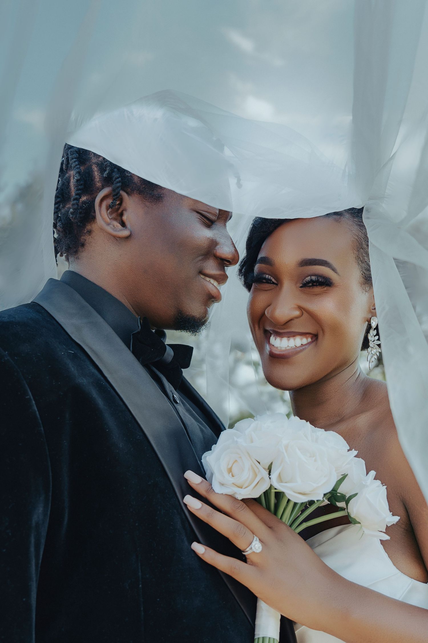 Romantic wedding portrait showing tender moment between newlyweds with white roses.