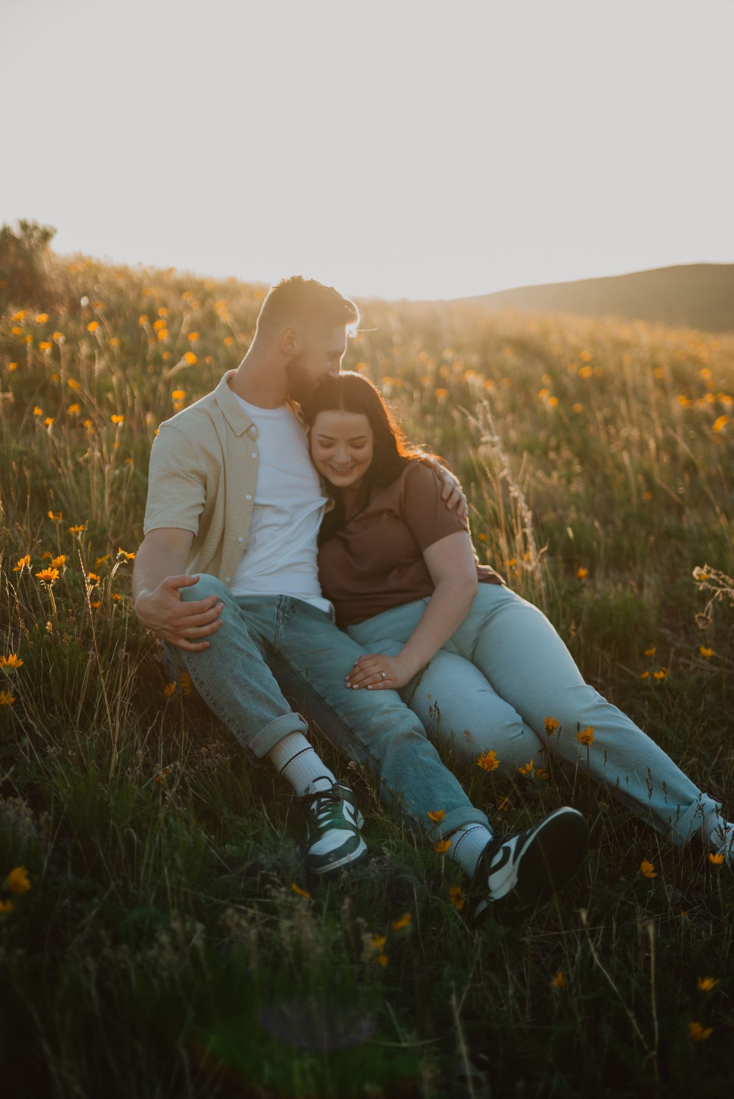 A couple relaxes together in a wildflower meadow during sunset.