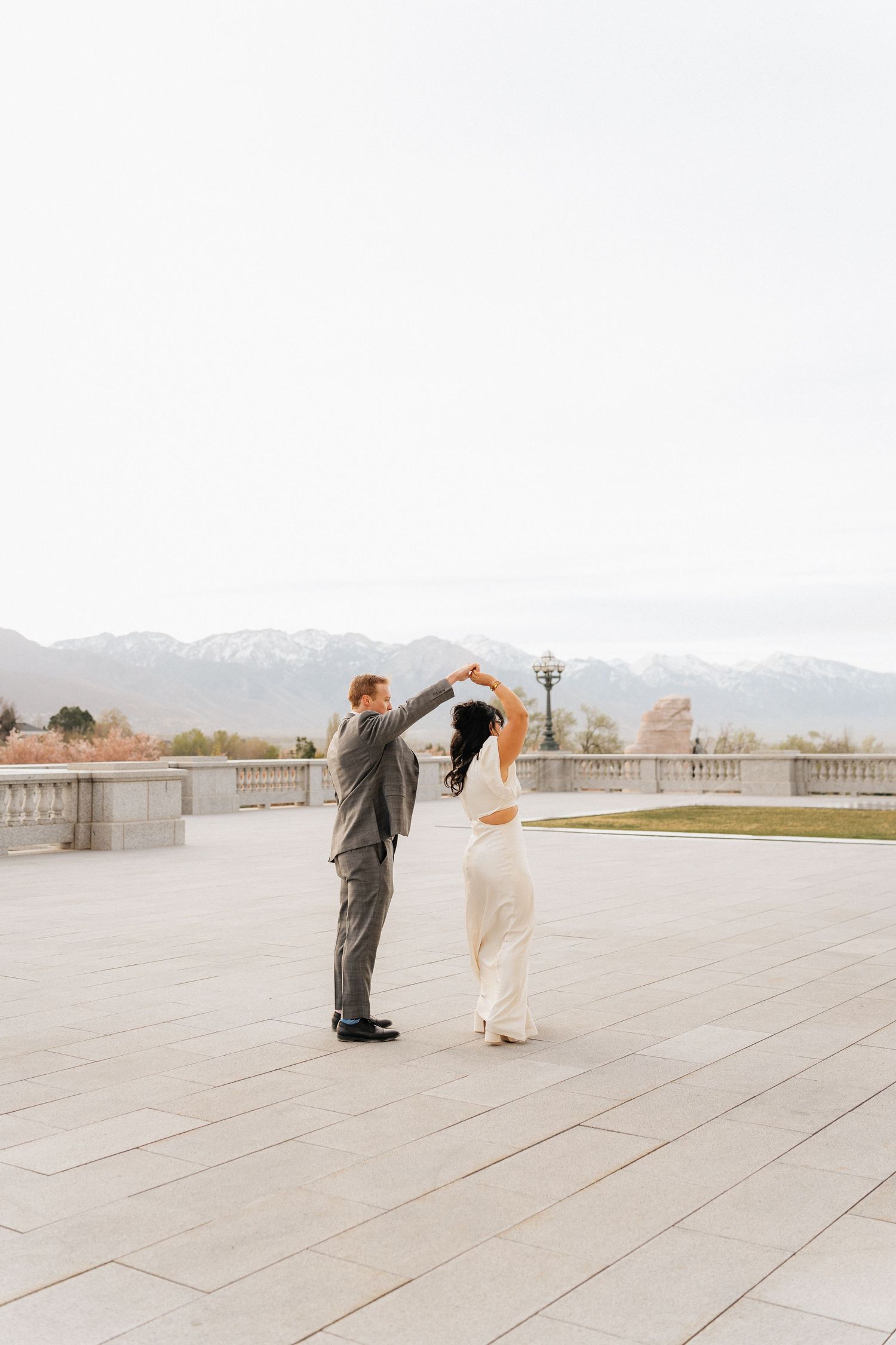 Bride and groom dancing on a terrace with snow-capped mountains in the background on their wedding day.