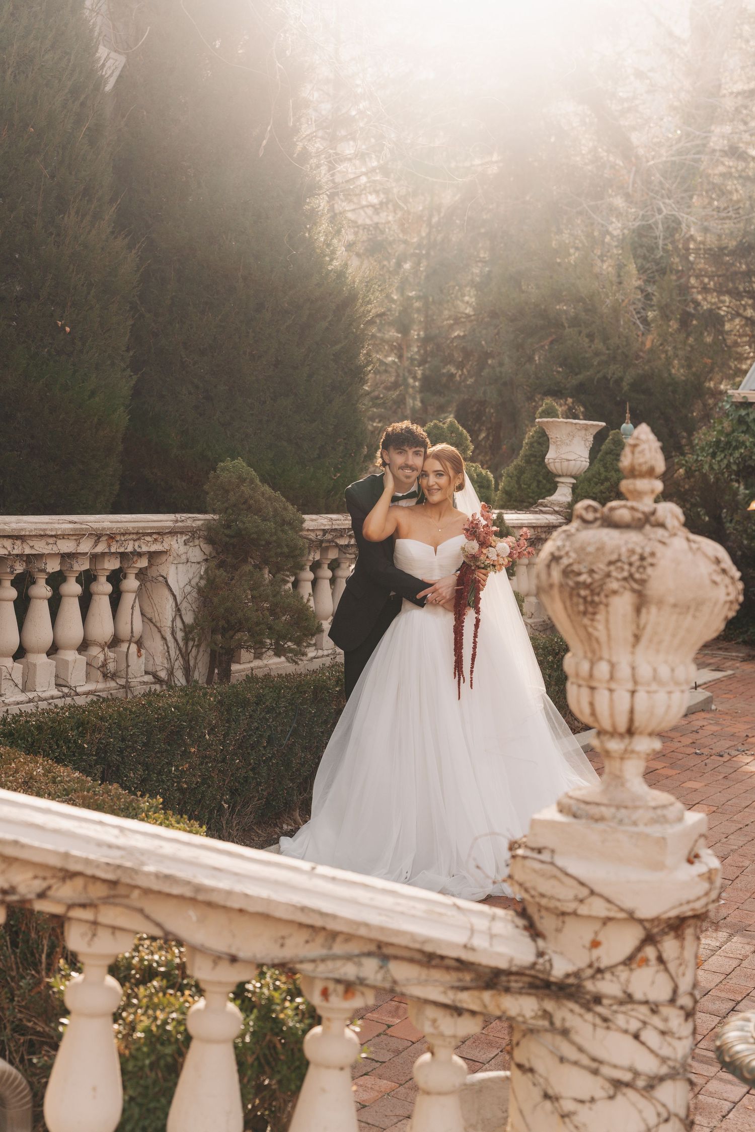 A dreamy wedding photo on a misty stone terrace with ornate balustrades and classical garden urns.
