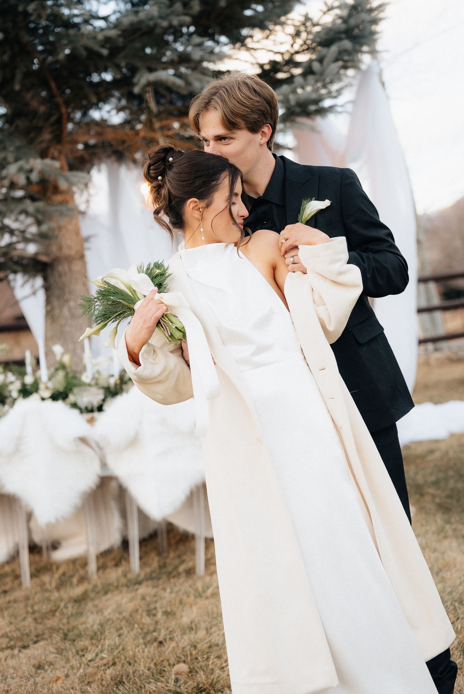 Couple in wedding attire shares a tender moment during an outdoor winter photoshoot in Utah.