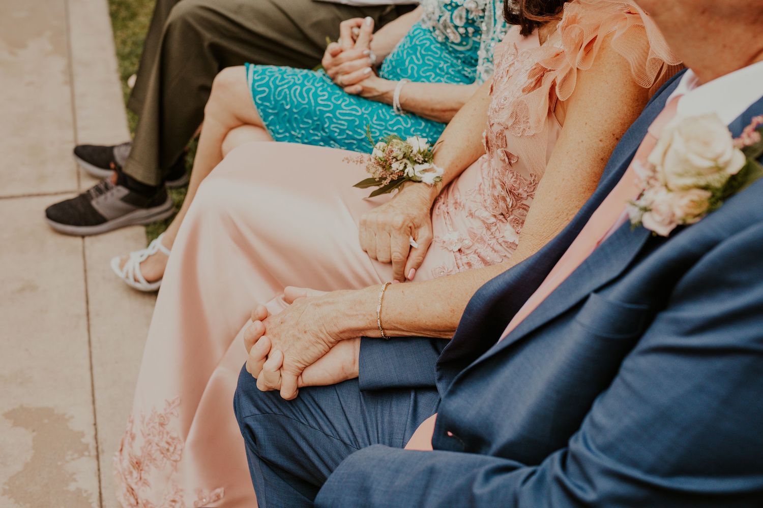 Close-up details of formal attire in teal and pink tones at an outdoor wedding.