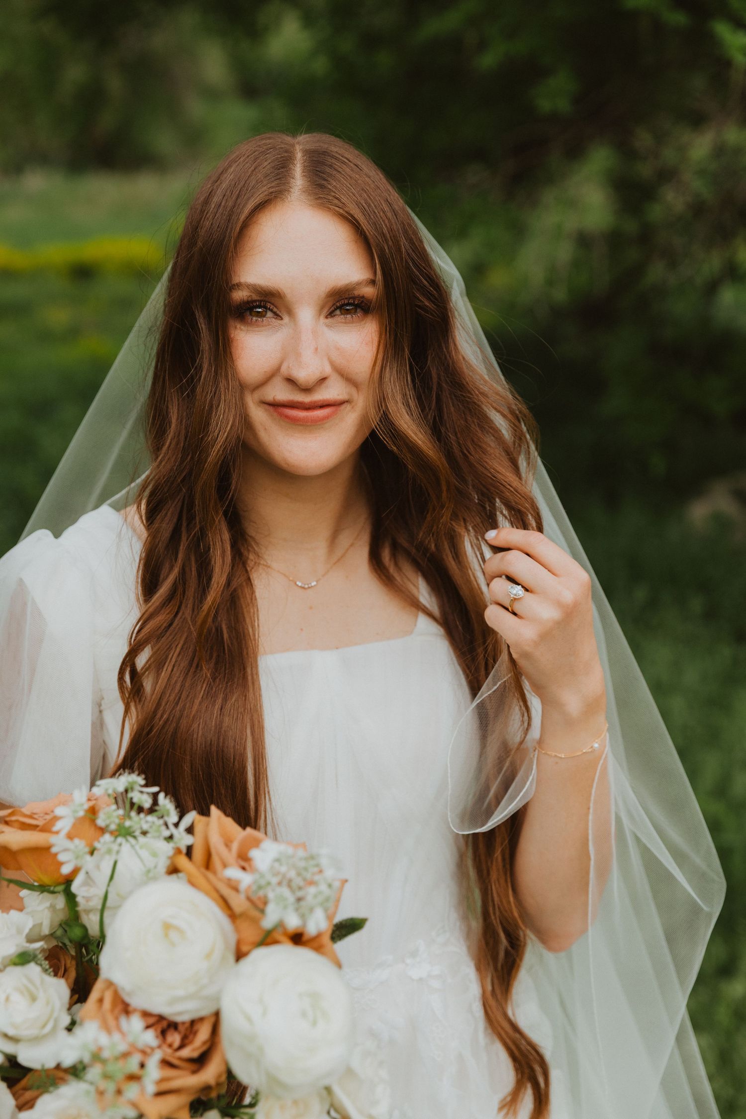 Ethereal bridal portraits featuring flowing veil and rustic peach and white bouquet in garden setting.