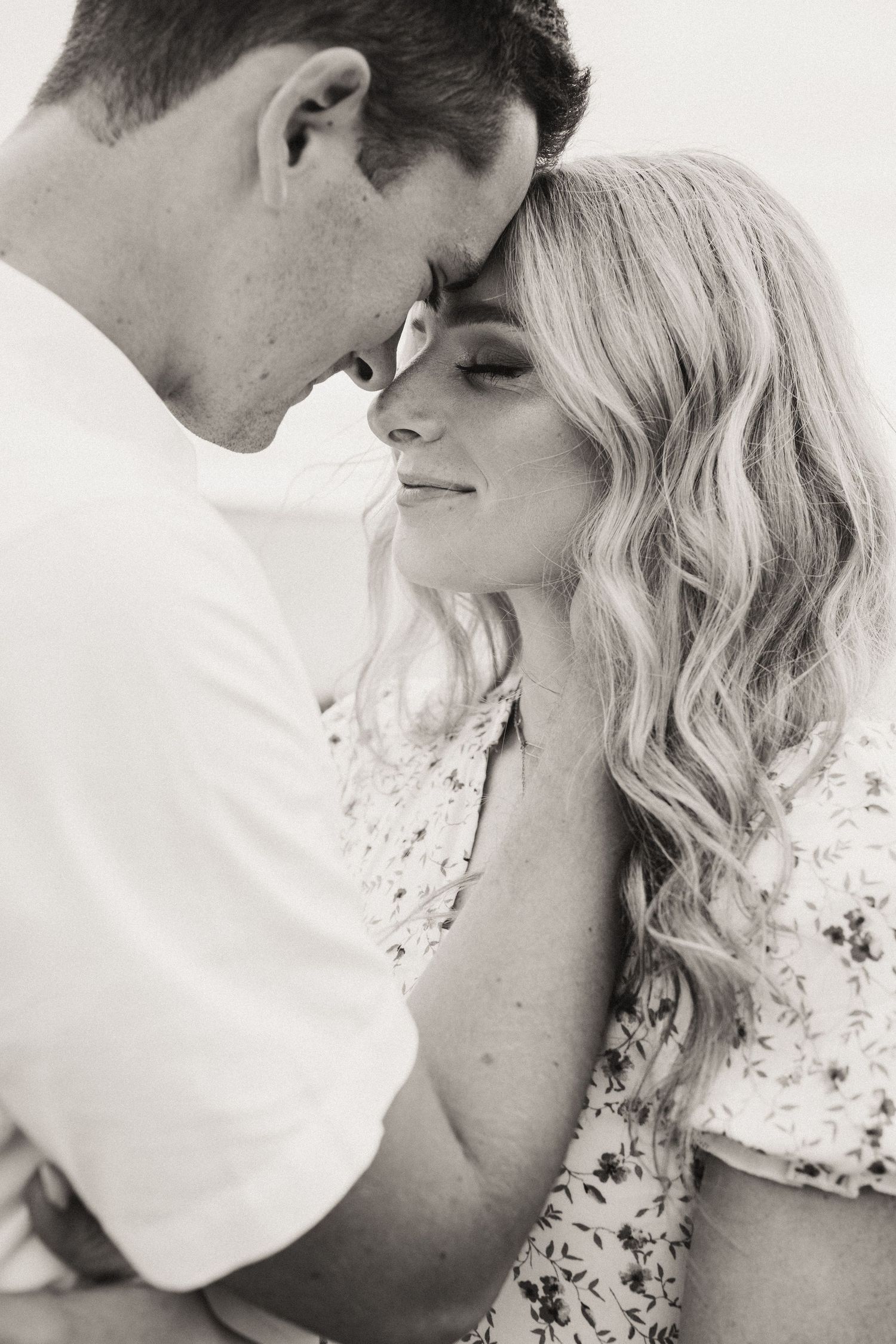 Intimate black and white close-up portrait of a couple sharing a tender moment.