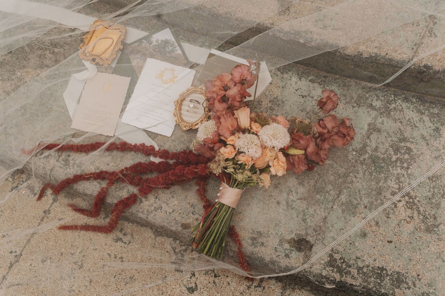 A rustic table surface with scattered dried flowers, ribbons, and floral arrangements in muted autumn tones.