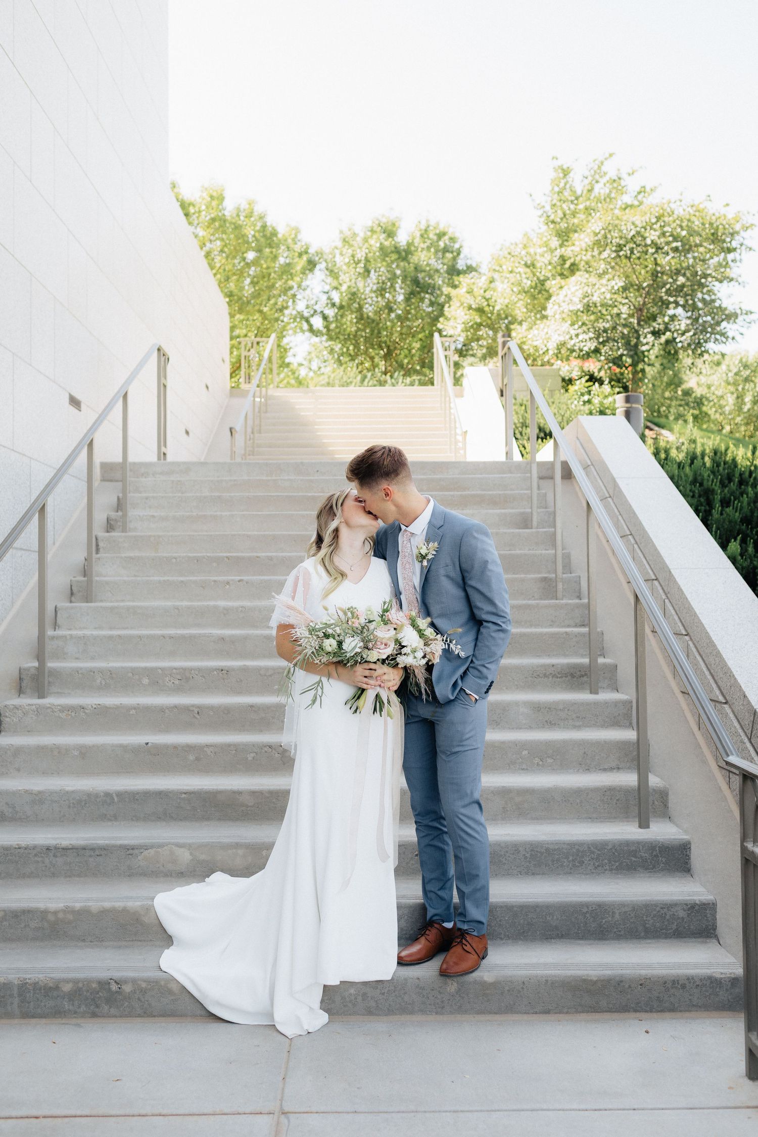 Wedding couple sharing intimate moments on concrete steps in outdoor setting.