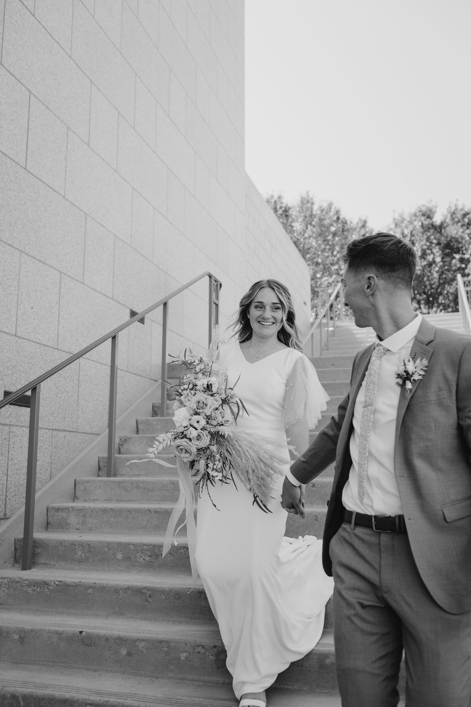 Candid black and white wedding photos showing playful moments on concrete steps.
