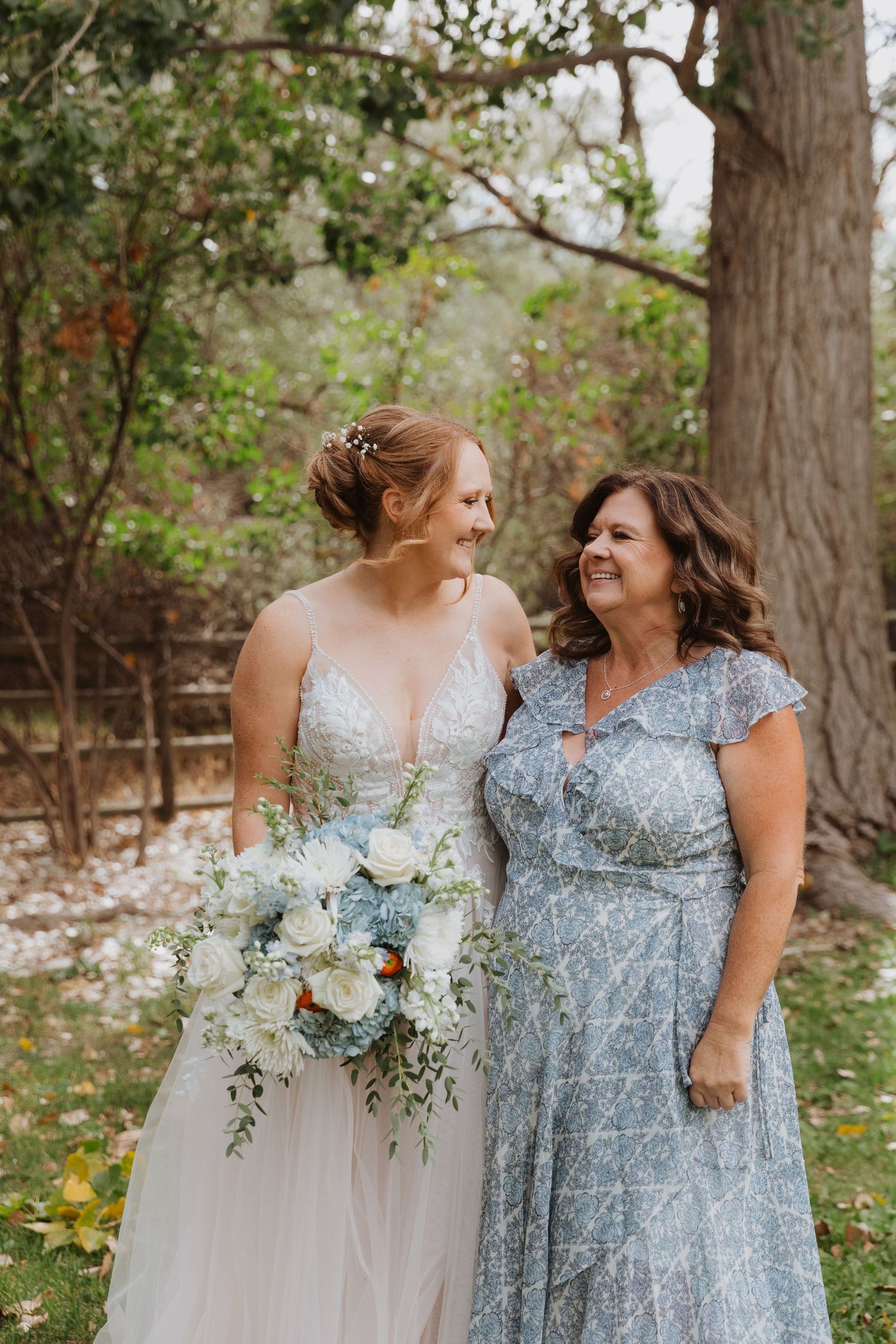 Two people in formal attire share a joyful moment while holding white floral bouquets.