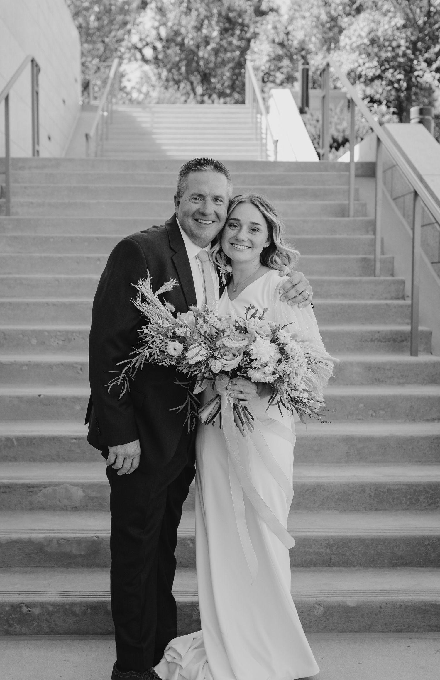 Black and white wedding portraits on architectural steps showing joyful candid moments.
