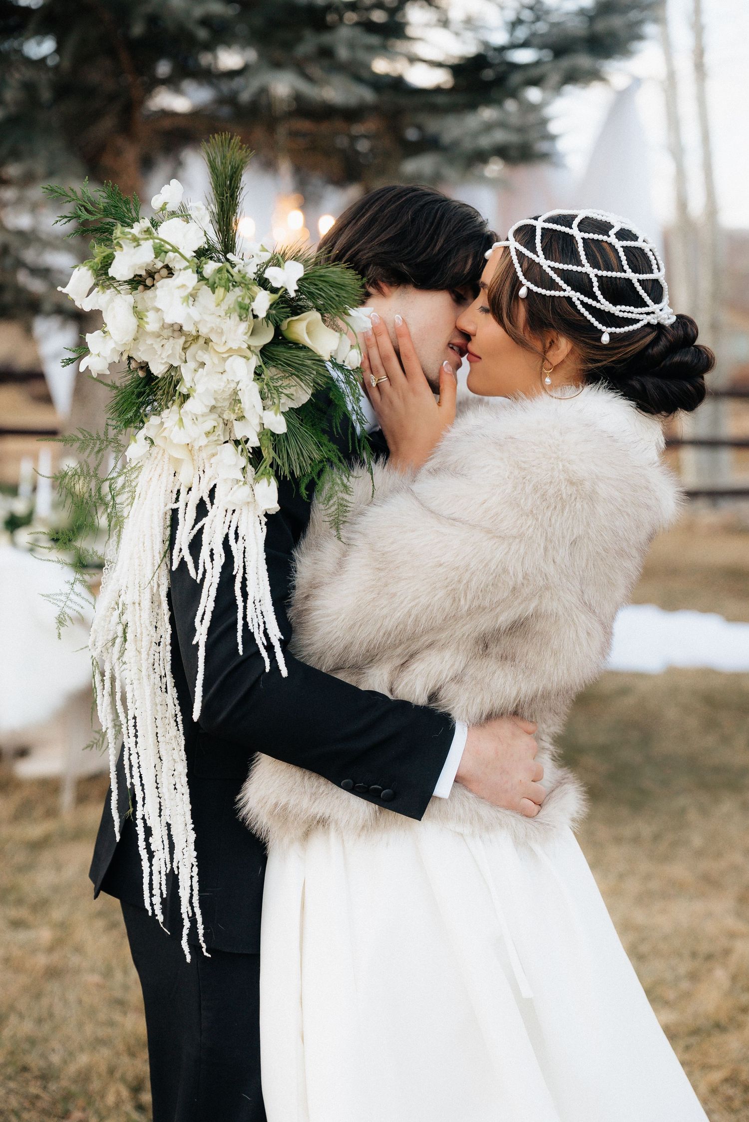 Wedding couple embraces in a winter outdoor setting with white floral decorations in Utah.