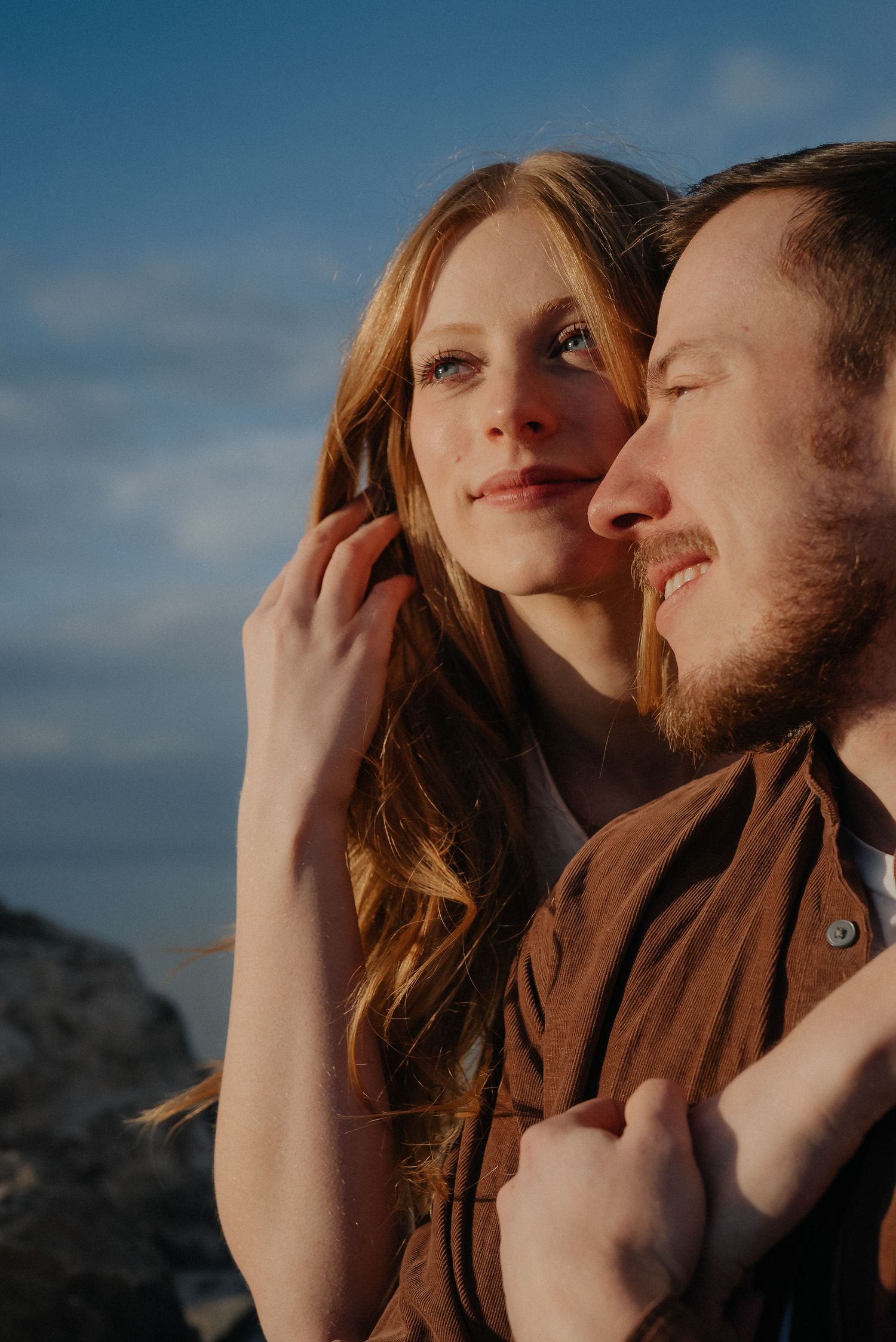 Intimate close-up portrait of couple against blue sky during sunset.