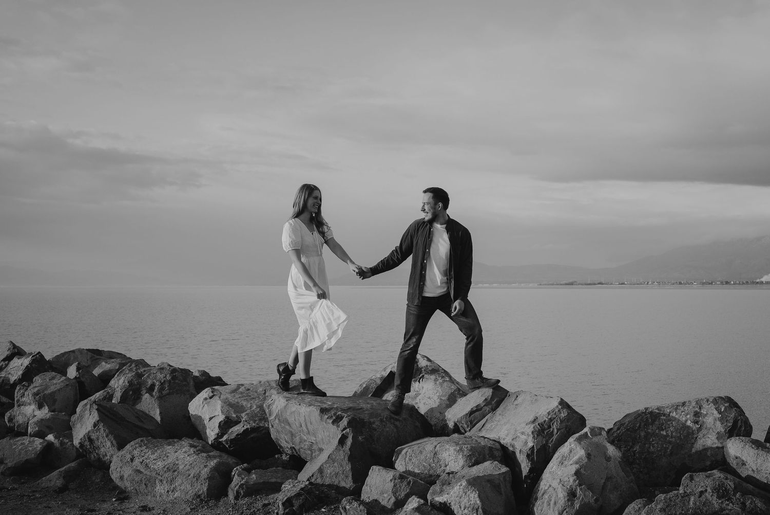 Black and white photo series of couple exploring rocky terrain with dramatic sky.
