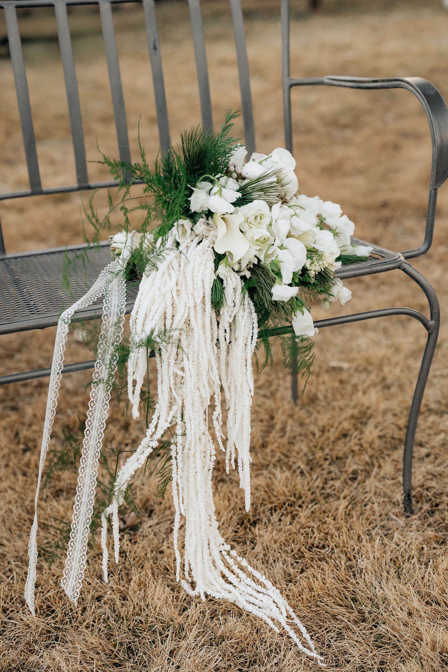White floral and greenery chair decorations adorn metal chairs at an outdoor wedding ceremony in Utah.