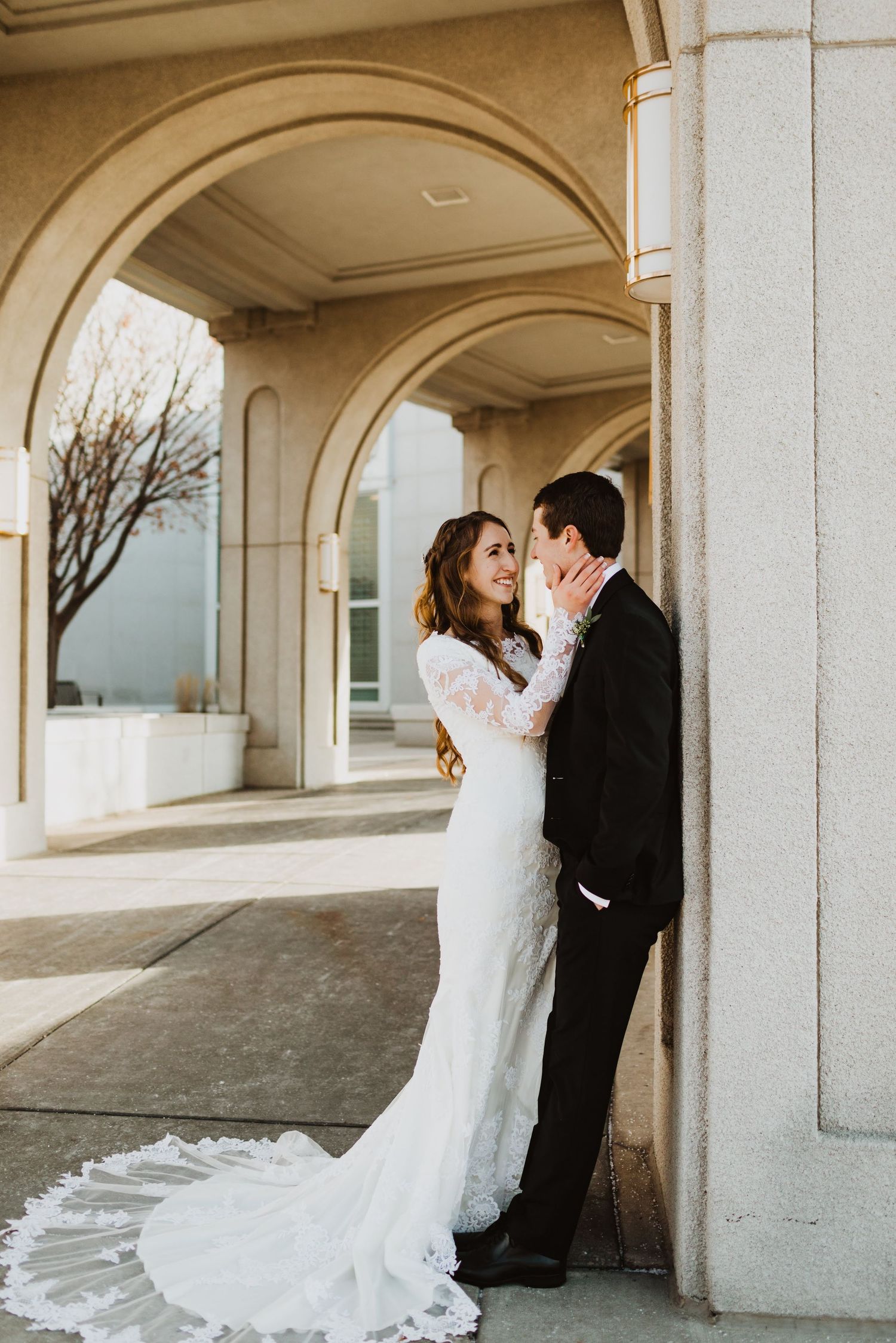 An elegant wedding photo under stone archways with dramatic architectural framing.