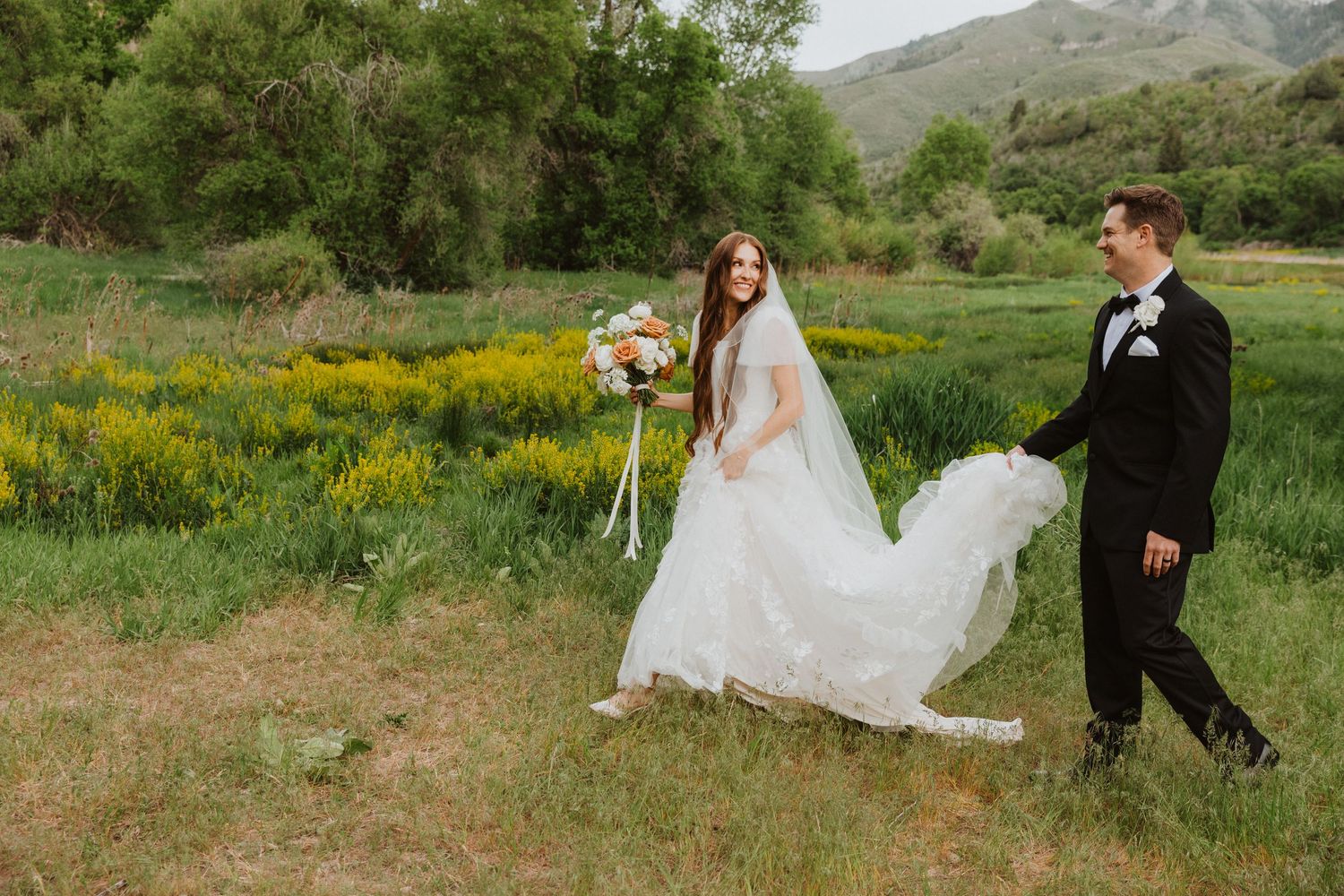 Romantic outdoor wedding photography session in a scenic mountain meadow filled with wildflowers.