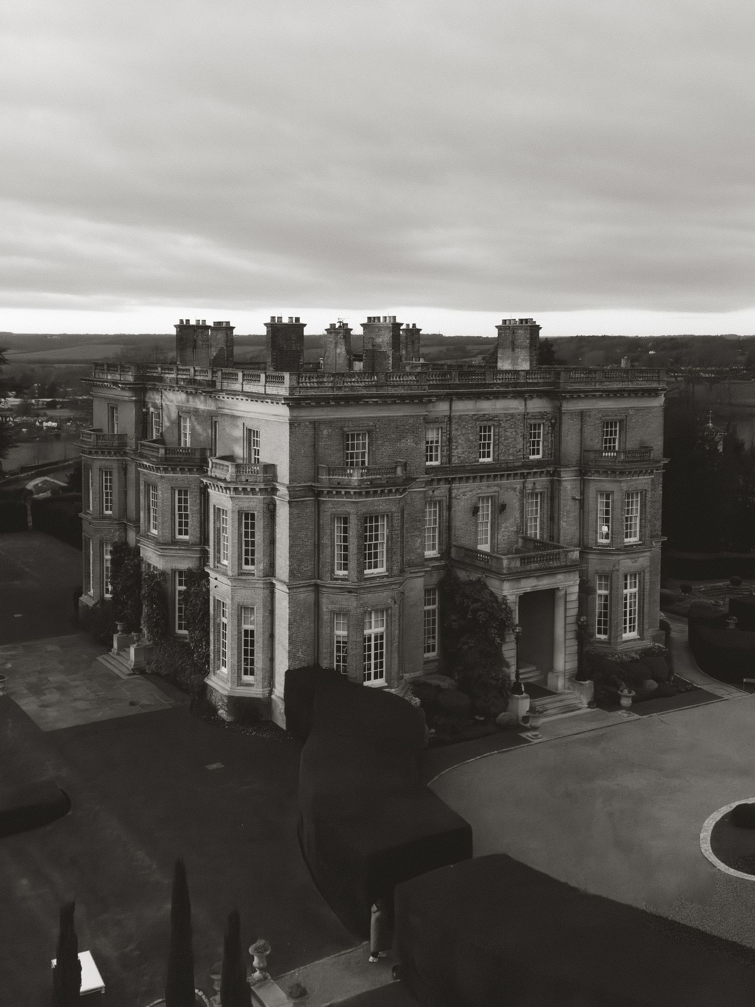 Panoramic view of a grand historic mansion with Georgian architecture under cloudy skies.