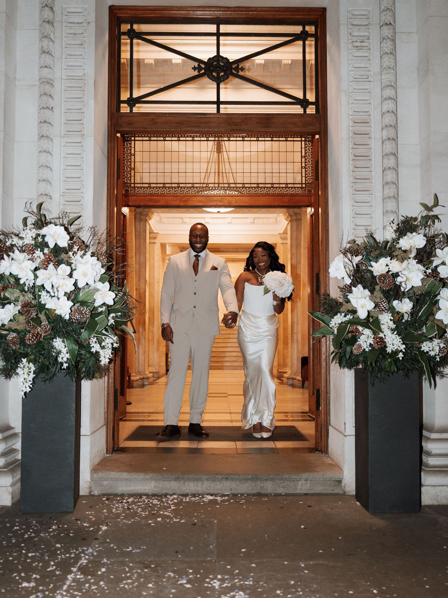 Grand entrance of wedding venue decorated with white floral arrangements and elegant columns.