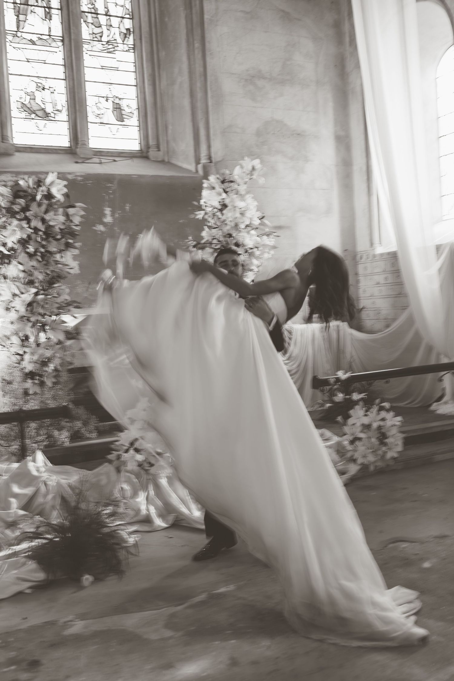 Artistic black and white photos of flowing wedding dress movement in a chapel setting.