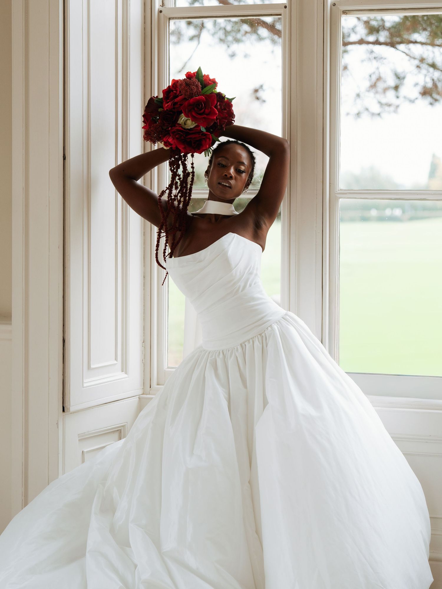 Flowing white wedding dress photographed against bright windows.