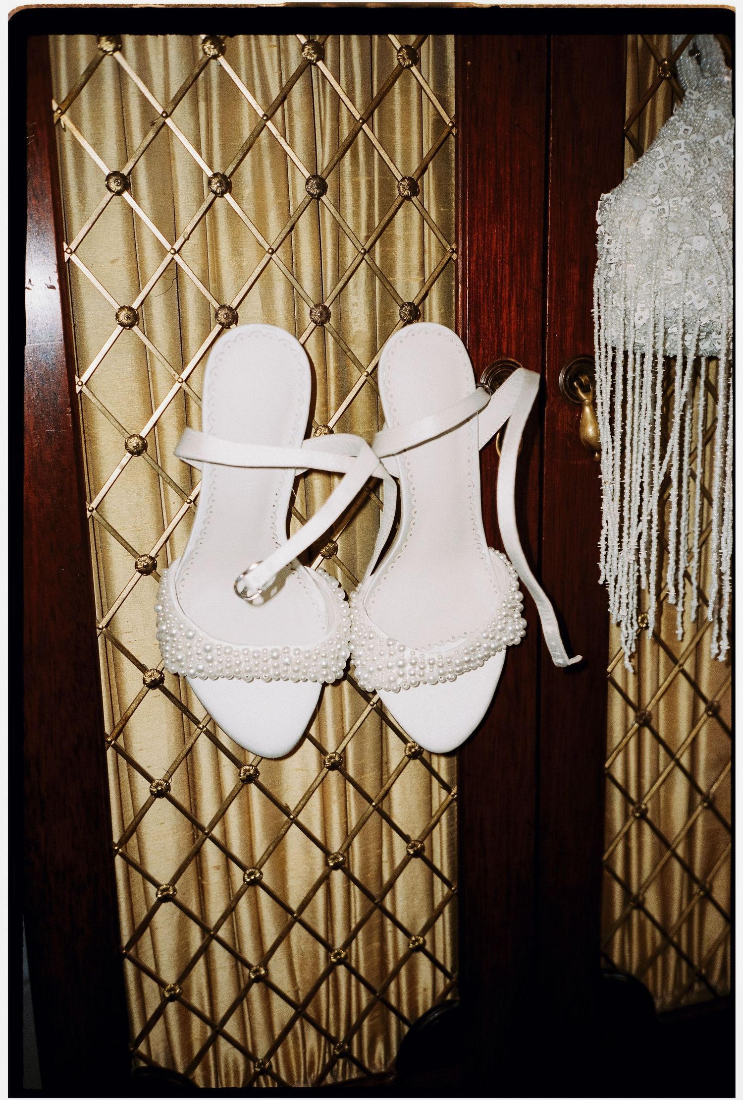 A collection of white bridal shoes displayed against a patterned gold curtain backdrop.