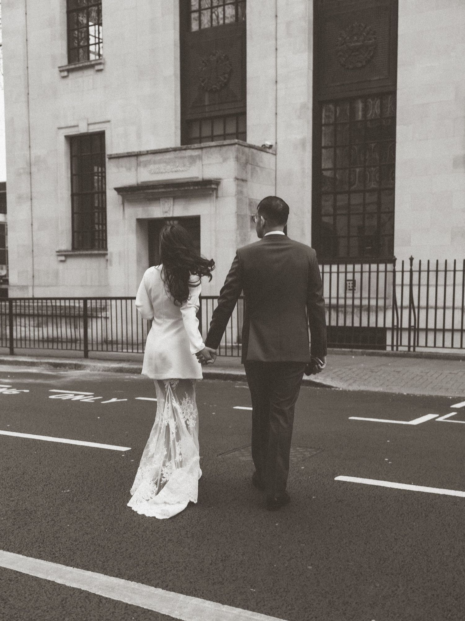 Black and white photo of couple walking outside historic building.