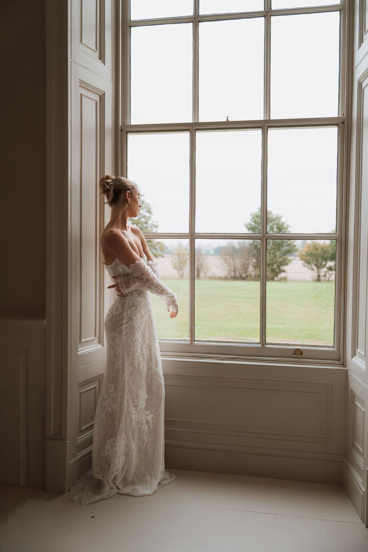 Ethereal bridal portrait in a sunlit room with large windows.