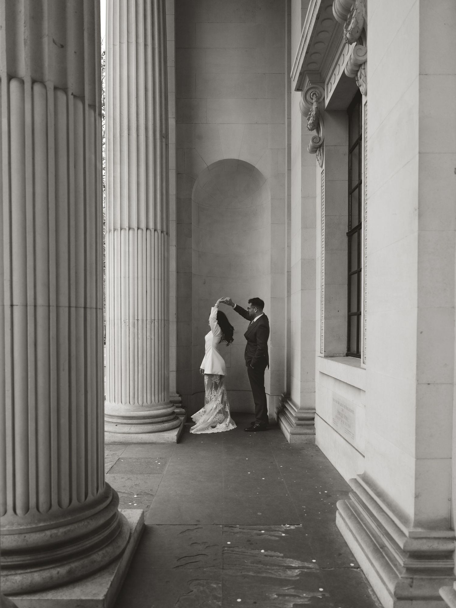 Architectural details of classical colonnade with wedding couple in the distance.