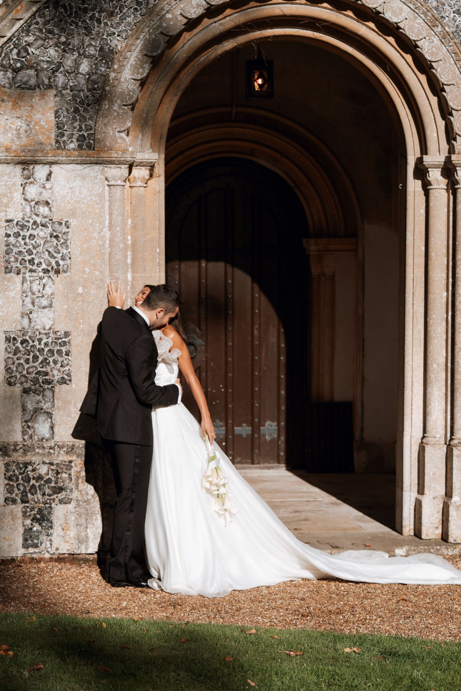 Wedding couple posing under stone archways of a historic building.