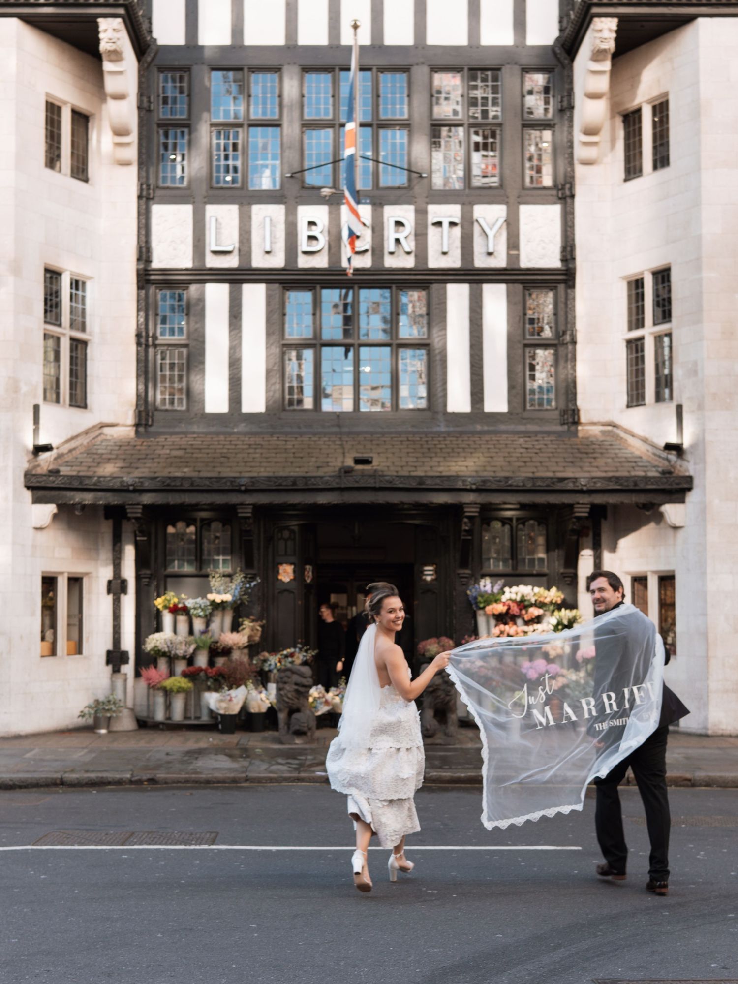 A wedding couple poses in a series of romantic shots outside a historic building with arched windows.