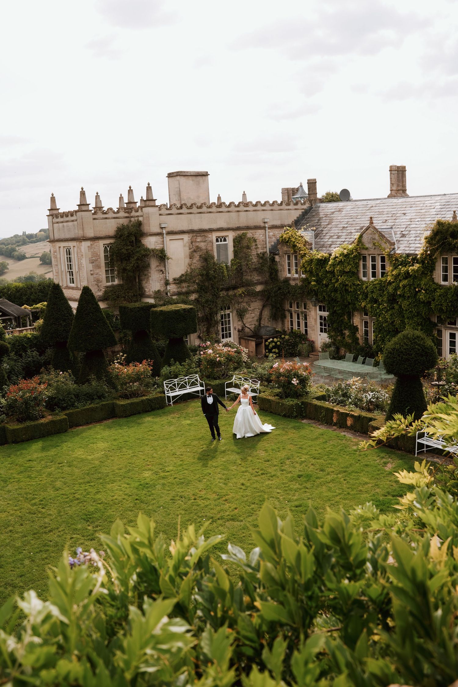 A panoramic view of a grand historic estate with manicured gardens and stone architecture.