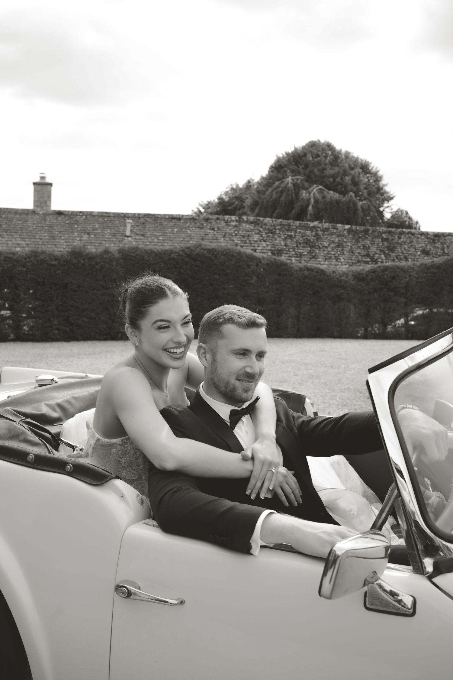 Newlyweds sharing intimate moments in a classic convertible car.