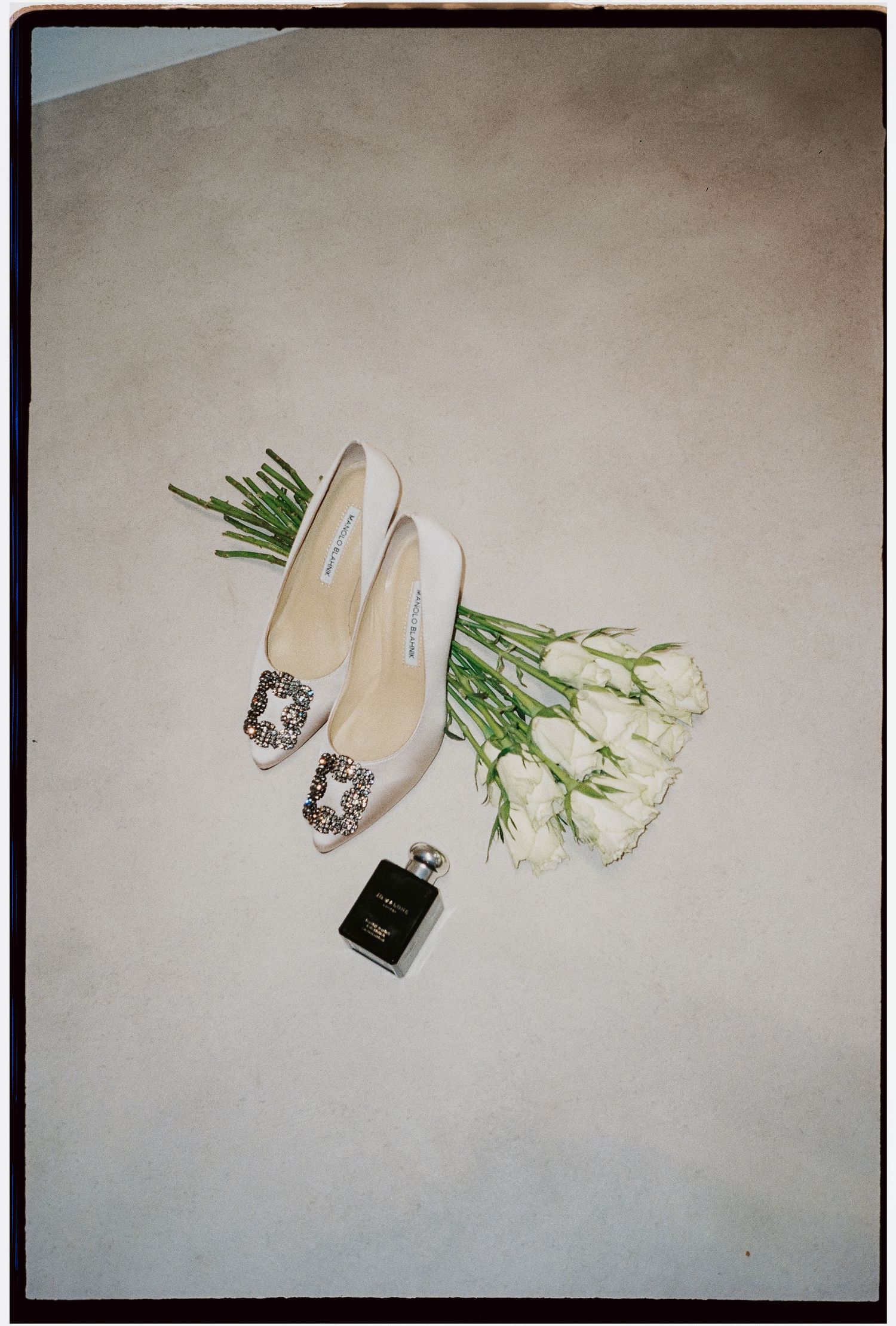 Wedding accessories flatlay with white heels, perfume bottle and tulips.