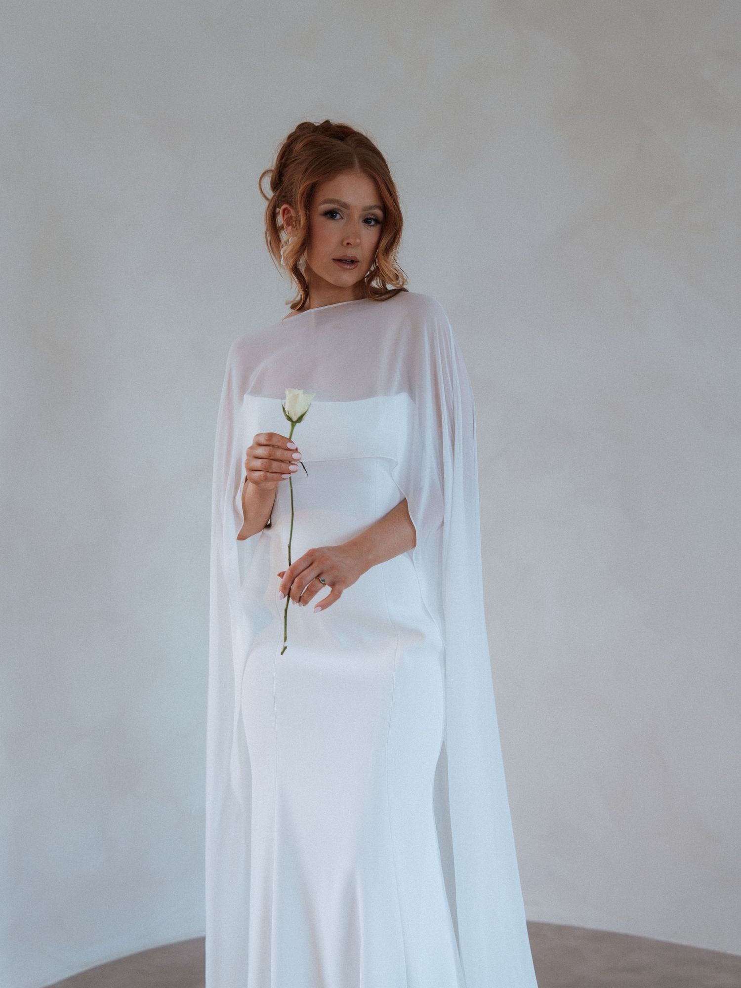 Minimalist bridal fashion shoot against white walls showcasing elegant white gowns and romantic styling.