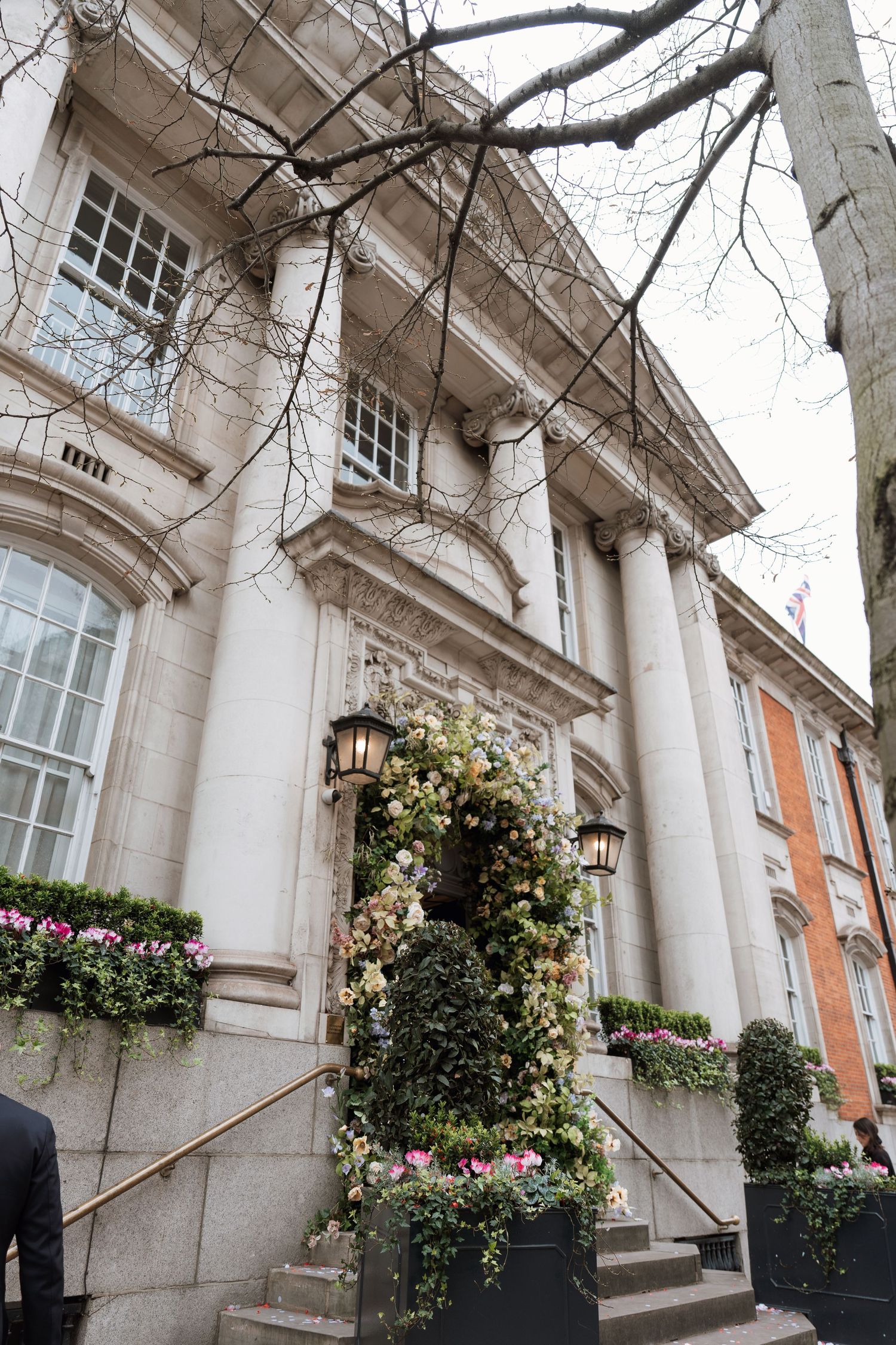 Elegant historic building entrance with white stone columns, climbing vines, and decorative flower boxes in Charleston.