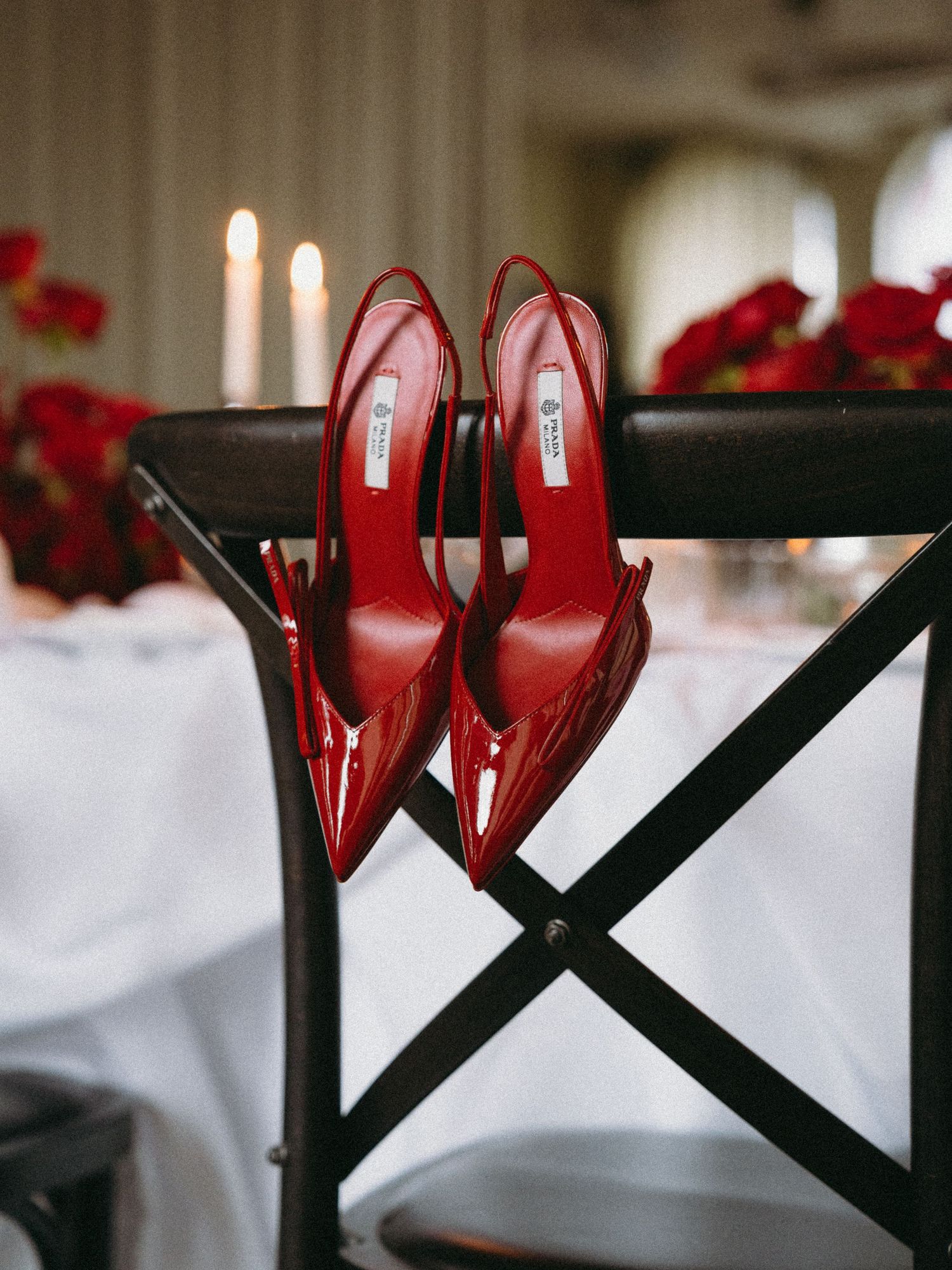 A pair of elegant red stiletto heels displayed against a black geometric stand with white and red decor in the background.