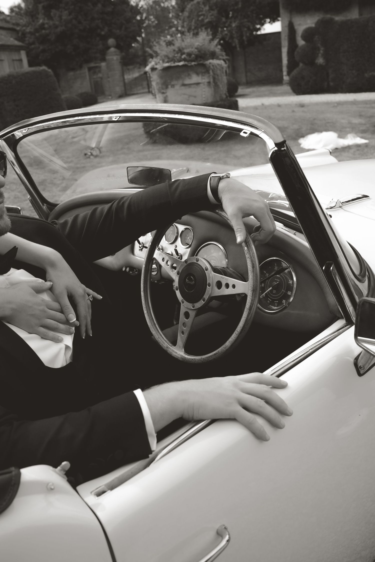 Artistic black and white close-up shots of hands on a classic car steering wheel.