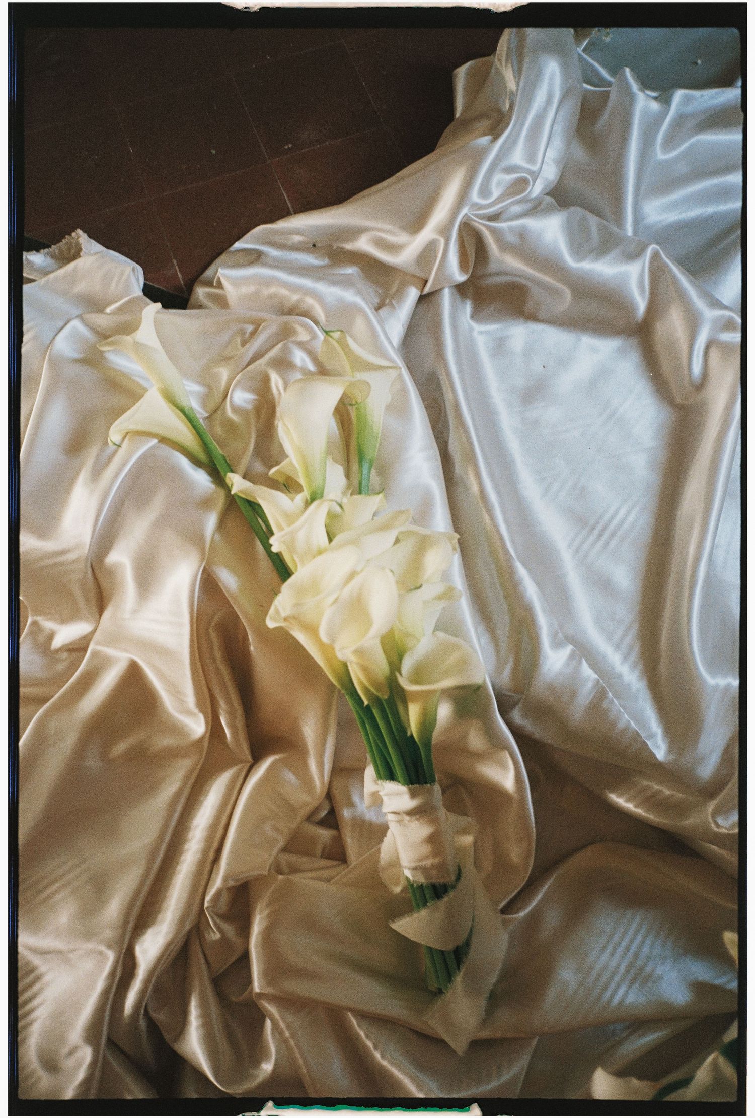 White calla lilies arranged on flowing silk fabric in an artistic still life composition.