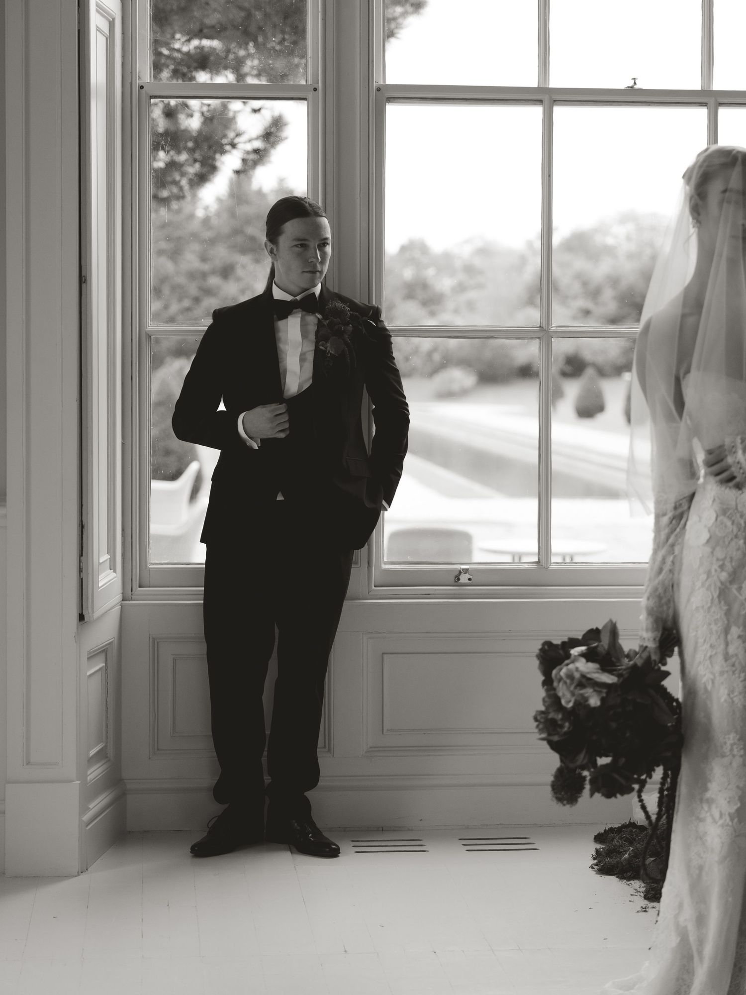 Black and white wedding portraits in elegant room with large windows.
