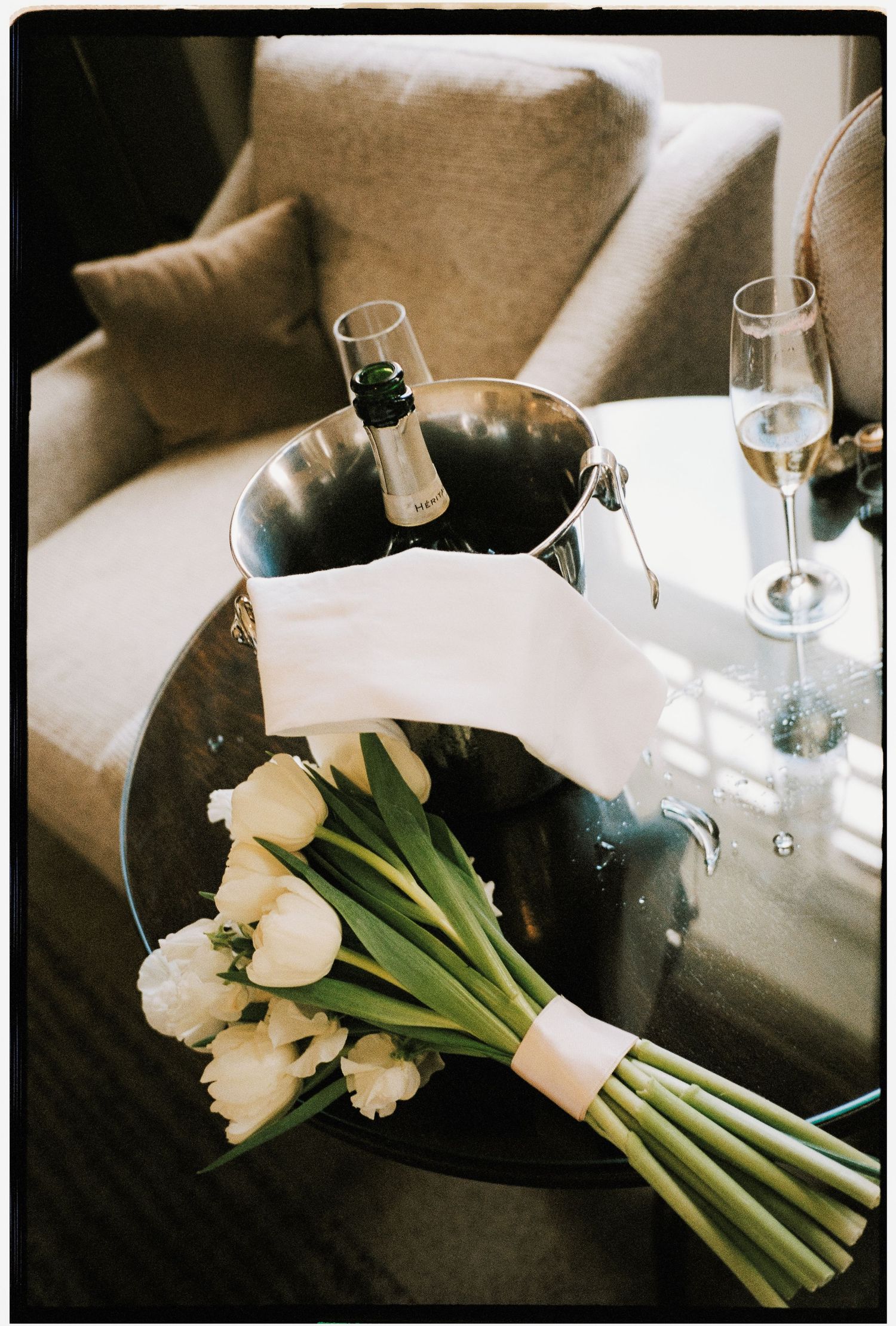 A white tulip bouquet rests on a dark couch, photographed in a soft, sepia-toned sequence showing different angles.
